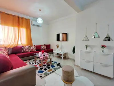 a living room with a red couch and a table at Stylish & Bright Apartment in Marrakech