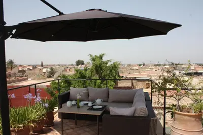 an umbrella on a balcony with a couch and a table at Riad La Villa Marrakech in Marrakech