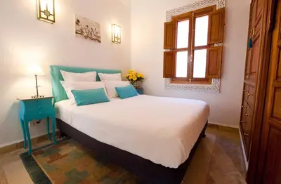 a bedroom with a large bed with a blue end table at Riad La Villa Marrakech in Marrakech