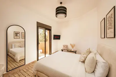 a white bedroom with a bed and a mirror at Cozy & Stylish Apartment in Marrakech in Marrakech