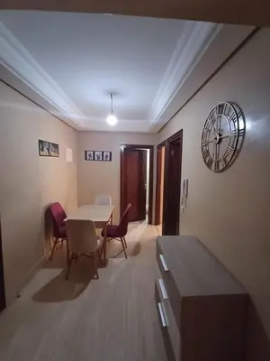 a living room with a table and chairs and a clock at Appartement familial résidence Hamza 2 chambres in Marrakech