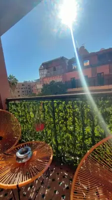 a patio with two tables and a light on a balcony at Appartement familial résidence Hamza 2 chambres in Marrakech
