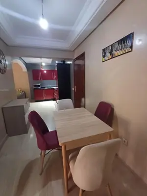 a dining room with a wooden table and chairs at Appartement familial résidence Hamza 2 chambres in Marrakech