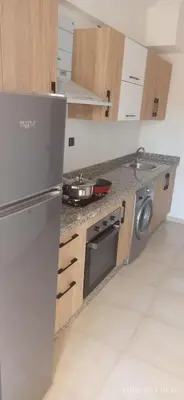a kitchen with a stainless steel refrigerator and wooden cabinets at luxurious and stylish apartment in Marrakech