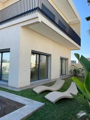 a house with two white chairs in the grass at Villa Rana in Marrakech