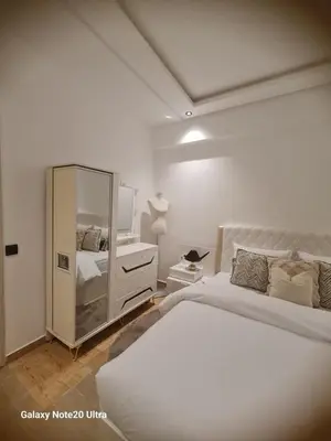 a white bedroom with a large bed and a mirror at Quiet studio in Marrakech