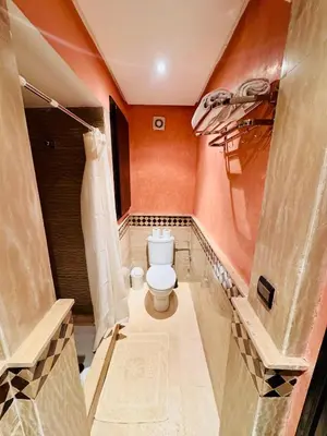 a bathroom with a toilet and an orange wall at Résidence Miramas 2 Cosy Appartment 2 in Marrakech