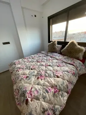 a bedroom with a bed with a floral bedspread and a window at Appartement 2 chombr salon a marrakech in Marrakech