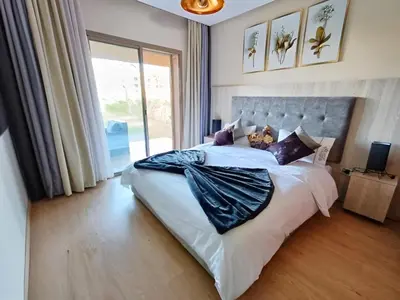 a bedroom with a large bed with a large window at Luxueux Appartement Prestigia Agate in Marrakech
