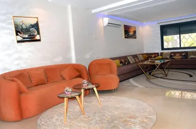 a living room with an orange couch and two tables at Burj malak in Marrakech
