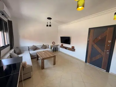 a living room with a couch and a table and a door at charming apartment close to airport Marrakech in Marrakech