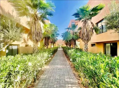 a pathway with palm trees and a building at Cozy appartement Marrakech in Marrakech