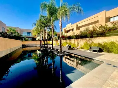 a pool of water with palm trees and a building at Cozy appartement Marrakech in Marrakech