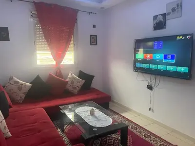 a living room with a red couch and a flat screen tv at MmAéroport Menara Résidence abrar mhamid 1 in Marrakech