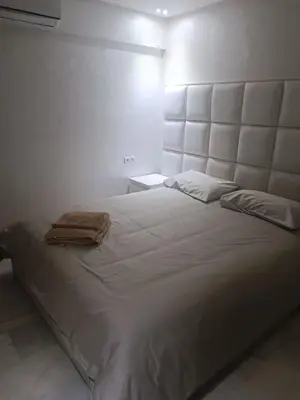 a bedroom with a large white bed with a large headboard at Modern apartment in the Heart of the City in Marrakech