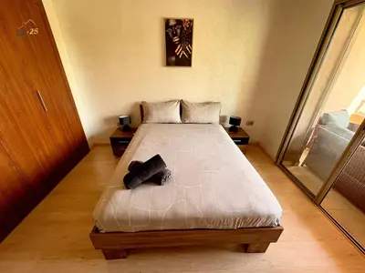 a bedroom with a large bed with two shoes on it at Appartement Prestigia Agate résidence avec piscine in Marrakech