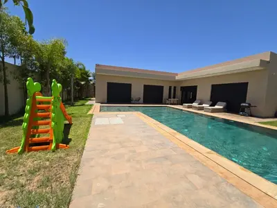 a swimming pool with a slide next to a house at Villa echwitter in Marrakech