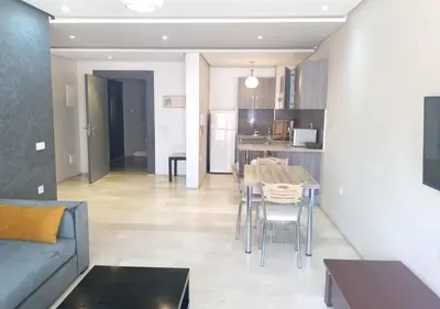 a living room with a couch and a table and a kitchen at Skyline Studios Hivernage in Marrakech