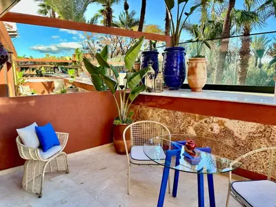 a patio with a glass table and chairs on a balcony at Yves Saint Laurent Jacuzzi Elegance in Marrakech