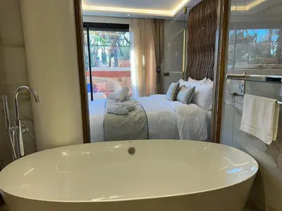 a bathroom with a tub in front of a bedroom at Yves Saint Laurent Jacuzzi Elegance in Marrakech
