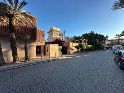 a cobblestone street with palm trees and cars parked at Yves Saint Laurent Jacuzzi Elegance in Marrakech