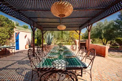 a patio with a table and chairs under a pergola at Villa Ferme de Coco in El Caïd Omar