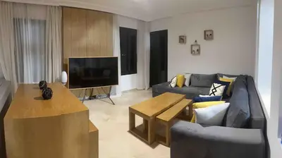 a living room with a couch and a tv at Marrakech River Palm in Dar Caïd Layadi