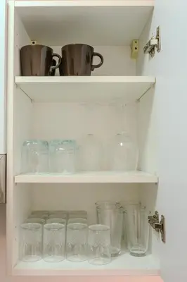 a shelf filled with glasses and pots and pans at Luxury 2BD in Prestigia Jade with Pool and Golf View in Marrakech