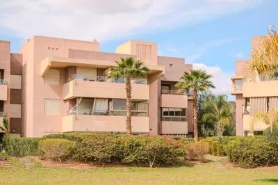 a building with palm trees in front of it at Luxury 2BD in Prestigia Jade with Pool and Golf View in Marrakech