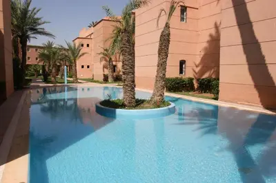 a swimming pool with a palm tree in front of a building at big house with swiming pool in Marrakech
