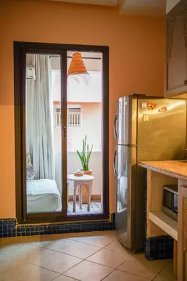 a kitchen with a refrigerator and a table with a window at Charm & Comfort in Majorelle, Close to YSL Museum in Marrakech
