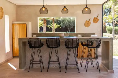 a kitchen with a counter with four bar stools at Villa Anna - Havre de paix in Oulad Ikhia