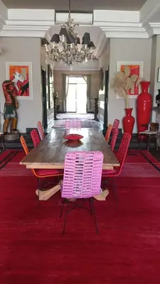 a dining room with a large table and pink chairs at Dar abie in Sraghna