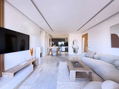 a living room with a couch and a tv at Charme Appt En Résidence Riad Garden Avec Piscine in Marrakech