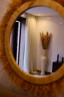 a mirror reflecting a room with a vase and a window at Luxueux DUPLEX au cœur Marrakech in Marrakech