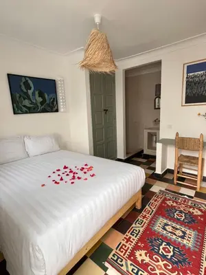 a bedroom with a white bed with red flowers on it at Dar Nook in Marrakech