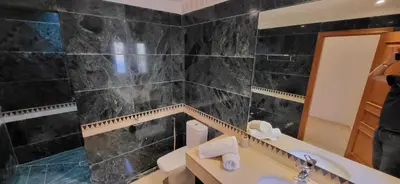 a black tiled bathroom with a sink and a mirror at La Plaza cœur de Gueliz in Marrakech
