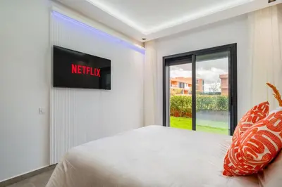 a bedroom with a bed with a television on the wall at Le Noria - Super logement Jardin & Piscine - Golf in Marrakech