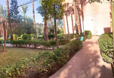 a walkway in front of a building with trees at Raid lkaram in Marrakech