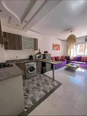 a kitchen with a table and a couch in a room at Confort et style en pleins centre ville in Marrakech