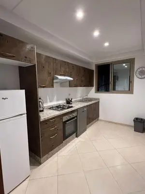 a kitchen with wooden cabinets and a white refrigerator at Appartement raffiné avec piscine au centre ville in Marrakech