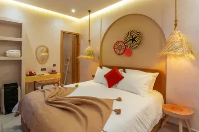 a bedroom with a bed with white sheets and red pillows at ALKHAYMA Medina in Marrakech