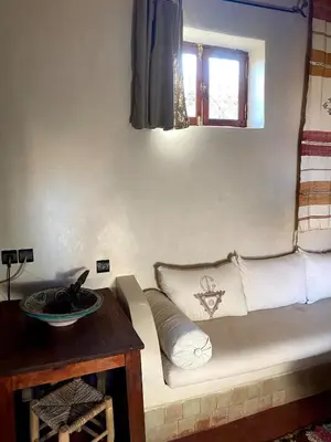 a couch in a room with a table and a window at DAR TITRIT Charming house with garden and pool in Akhatar