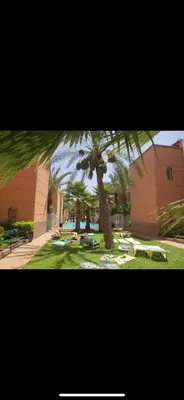 a park with a palm tree and a building at Riad abdel in Marrakech