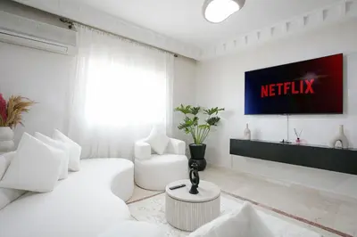 a living room with a white couch and a tv at La Perle Blanche Gueliz in Marrakech