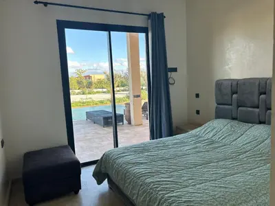 a bedroom with a bed and a sliding glass door at Villa avec piscine privée et sans vis à vis à Marrakech in Douar Nouaji