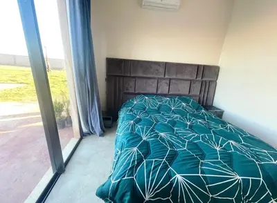 a bedroom with a bed with a green comforter at Villa avec piscine privée et sans vis à vis à Marrakech in Douar Nouaji