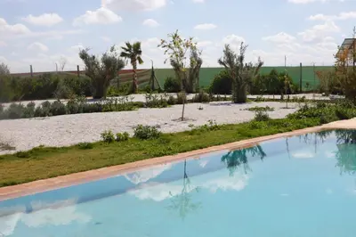 a swimming pool with a beach and palm trees at Villa avec piscine privée et sans vis à vis à Marrakech in Douar Nouaji