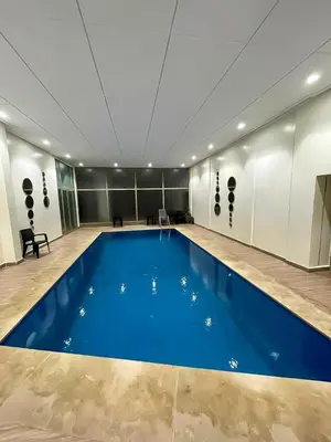 a large swimming pool in a building with a blue floor at Appartement à louer in Marrakech