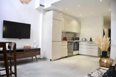 a kitchen with white cabinets and a tv on the wall at M17-Le Duplex-Balcon-Piscine-Majorelle in Marrakech